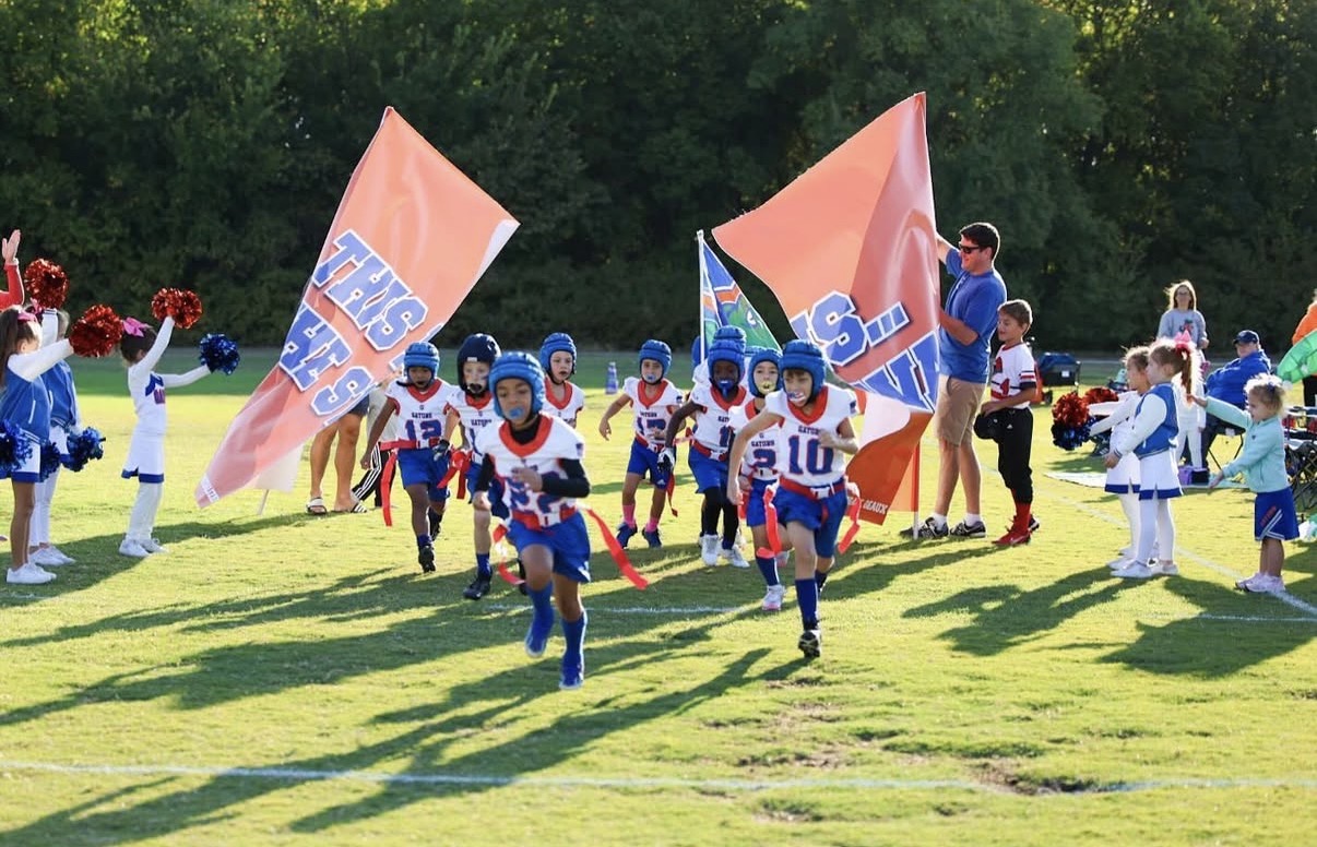Flag football team running onto the field through cheer flags